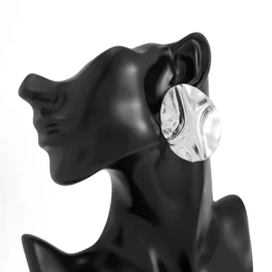 Detailed close-up of geometric irregular pleated silver metal earrings on black mannequin