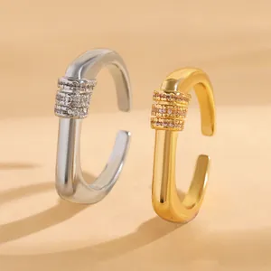 Close-up of minimalist open U-shaped rings with zircon inlay in gold and silver