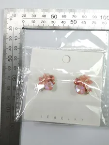 Macro view of pink flower stud earrings with measurement ruler for size reference