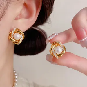 Dettaglio orecchini in oro con micro-pavé di zirconi e perla centrale, stile lussuoso.