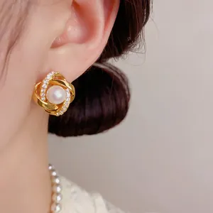 Primo piano di un elegante orecchino di perle d'oro intrecciato con molti micro-zirconi