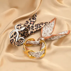 Close-up of hollow stainless steel bracelets with leopard and geometric silk accents
