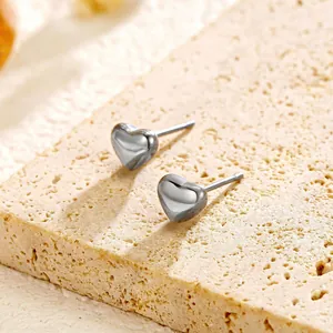 Detail view of minimalist polished silver titanium steel heart-shaped stud earrings on stone