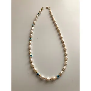 Detailed view of handmade Evil Eye necklace with baroque pearls and gold beads.
