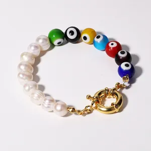 Macro view of colorful evil eye beads and natural freshwater pearls on a gold-clasped bracelet.