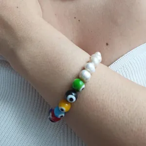Close-up of a colorful evil eye and pearl beaded bracelet worn on a wrist.