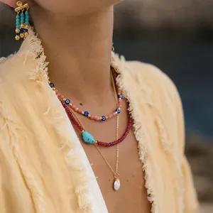 Close-up detail of layered beaded Evil Eye necklaces with pearl and turquoise pendants