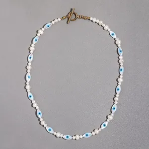 Close-up detail of evil eye motif beads and white pearls on a gold toggle necklace