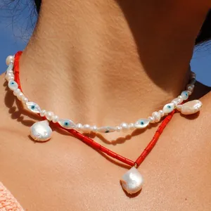 Close-up detail of double-layer evil eye pearl necklace with red beads and baroque pendants