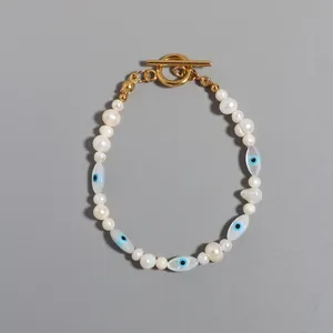 Detailed view of an Evil Eye charm and pearl necklace with a gold toggle clasp.