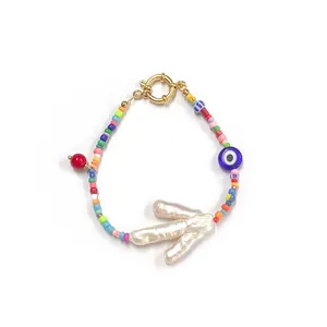 Close-up of colorful beaded necklace with evil eye charm and baroque pearl pendant