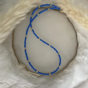 Macro detail of a minimalist blue and gold seed bead necklace on stone display base