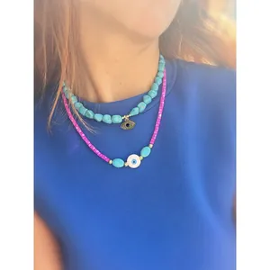 Close-up of colorful evil eye beaded layered necklace on model showing textures