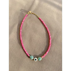 Detailed view of a pink beaded evil eye necklace with turquoise accents and gold chain
