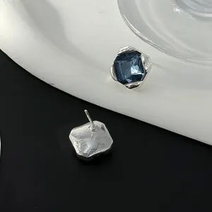 Gedetailleerd beeld van vierkante blauwe oorknopjes met onregelmatige zilveren zetting