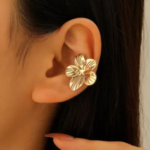 Close-up detail view of a textured gold flower ear cuff earring worn on a model's ear