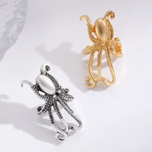 Detail of gold and silver octopus ear clips with pearl-like stones on white surface.