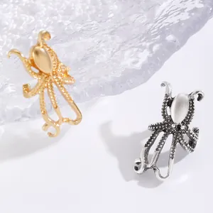 Macro detail of textured octopus shaped ear clips in vintage gold and silver finishes