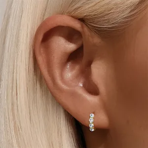 Nahaufnahme eines minimalistischen 6mm Goldohrrings mit vier Kristallen am Ohr