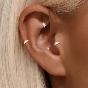 Nahaufnahme eleganter goldener Huggie-Ohrringe mit funkelnden Kristallen am Ohr eines Models
