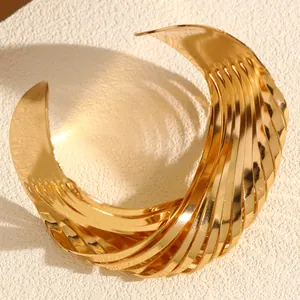 Macro view of the textured gold finish and multi-layered twisted design of the cuff bracelet.