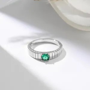 Primo piano dettagliato di un anello in acciaio al titanio con gemma verde tonda.