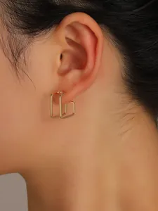 Close-up of a minimalist gold geometric hollow square hoop earring on a model ear