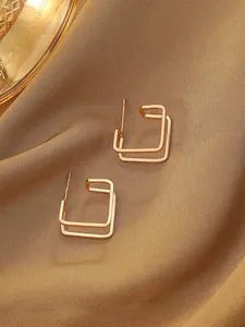 Close-up of gold double-layered rectangular hollow geometric stud earrings on satin