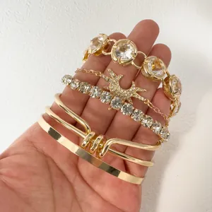 Close-up detail of layered gold punk bracelets featuring oversized crystals and charms