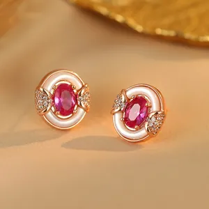 Detailed macro view of rose gold stud earrings featuring a central pink gemstone and white enamel
