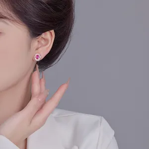 Close-up detail of a vintage rose gold stud earring with a pink gemstone on a model's ear