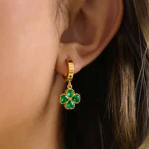 Close-up of 18K gold-plated clover earring with green gemstones on ear, elegant detail