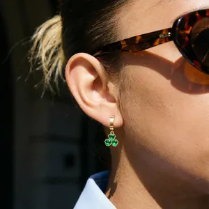 Elegant gold shamrock hoop earrings featuring three heart-shaped green gemstones.