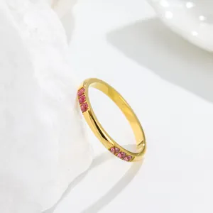 Close-up detail of a gold titanium steel ring with sparkling pink gemstone inlay