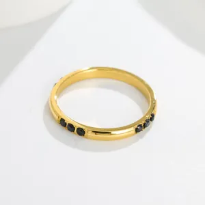 Close-up of gold titanium steel ring with black inlaid stones on white background.