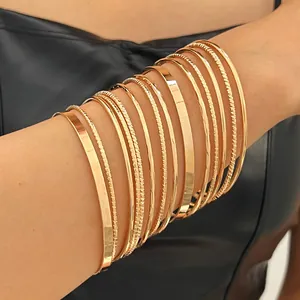 Detailed view of multiple gold-finished ethnic style metal bangles stacked on an arm