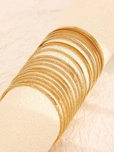 Close-up of ethnic gold alloy bangle set with various hammered and plain textures