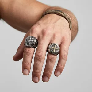 Gedetailleerde macro-opname van vintage Sint-Benedictuskruisringen aan een mannenhand