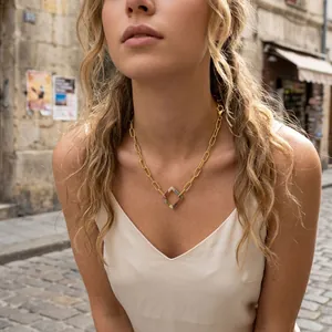 Gold paperclip chain necklace with rainbow zircon square pendant on a model in street.