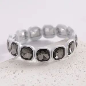 Dettaglio macro di un bracciale elastico bianco con gemme fumé quadrate sfaccettate