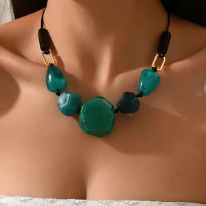 Detail view of ethnic irregular green resin stone necklace on model collarbone