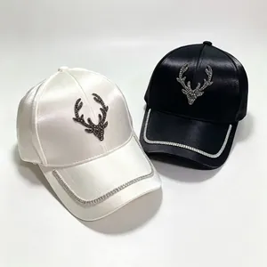 Detailed shot of black and white satin baseball caps with rhinestone deer head design