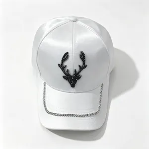 Detailed view of white satin baseball cap with rhinestone deer head and chain trim