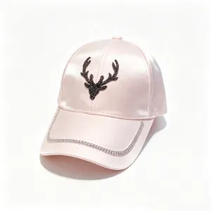 Detail view of the rhinestone deer head and chain on this elegant pink satin baseball cap.