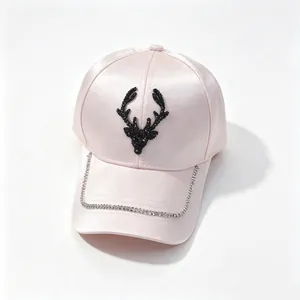 Close-up of pink satin baseball cap featuring a rhinestone deer head and chain detail