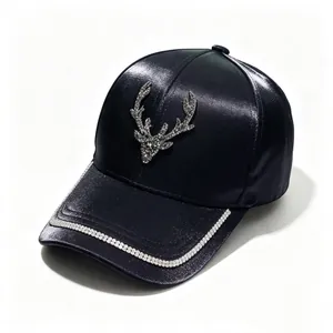 Close-up detail of a navy satin baseball cap with a rhinestone deer head and chain decoration