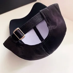 Close-up view of a black satin baseball cap with an adjustable metal buckle strap.