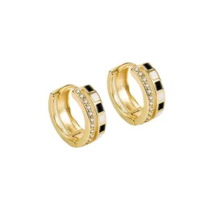Detailed view of gold hoop earrings with black and white enamel squares and pavé stones.