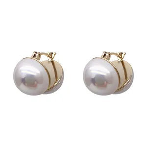 Close-up detail of elegant gold-toned hoop earrings featuring large lustrous white pearls.