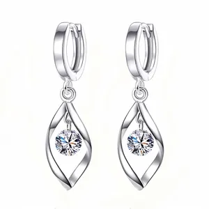 Macro detail of silver geometric twist drop earrings with sparkling round zirconia stone.
